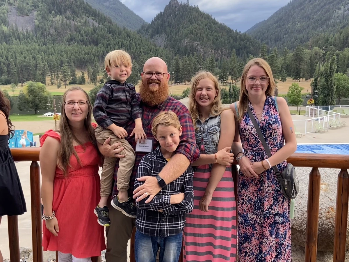 Bryce and his family together with forested mountains behind them.